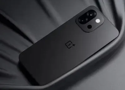 A sleek, matte black OnePlus smartphone (possibly the OnePlus 15 concept) with a dual camera setup and the OnePlus logo on the back, resting on a dark, reflective surface.